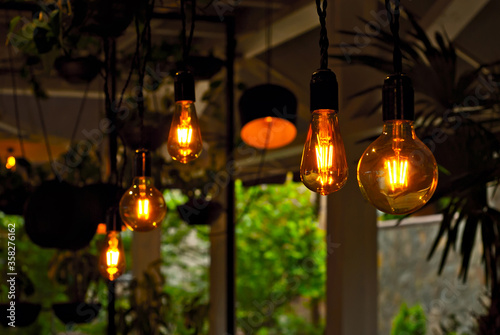 Yellow light bulbs as a design element. Greens and flowerpots in the background. Layout for interior design.