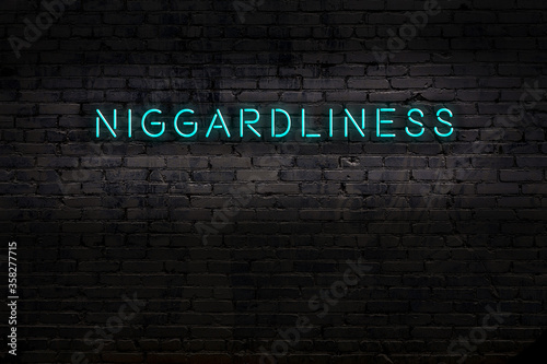 Neon sign. Word niggardliness against brick wall. Night view photo