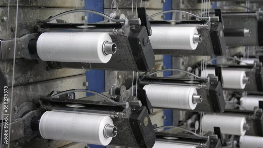 Rows of white reels with ropes making plastic sacks in a modern production plant Rows of white reels with ropes making plastic sacks in a modern production plant