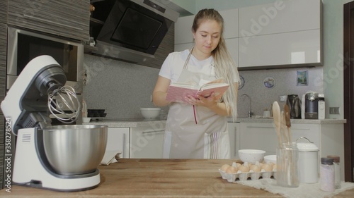 Housewife reading recipe in cookery book in the kitchen