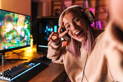 Image of excited girl taking selfie photo while playing video game photo