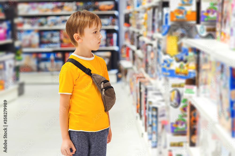 Many toys around. Kids shop. Sales, discounts and shopping. Cute boy selecting toys in store.