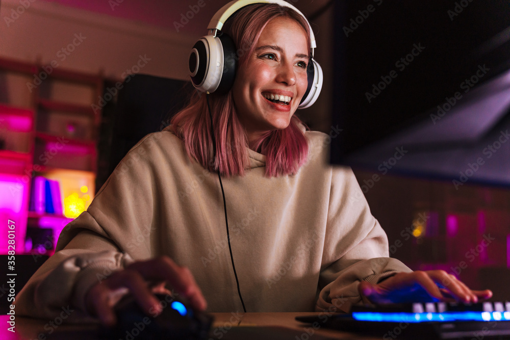 Image of joyful girl smiling and playing video game on computer - obrazy, fototapety, plakaty 