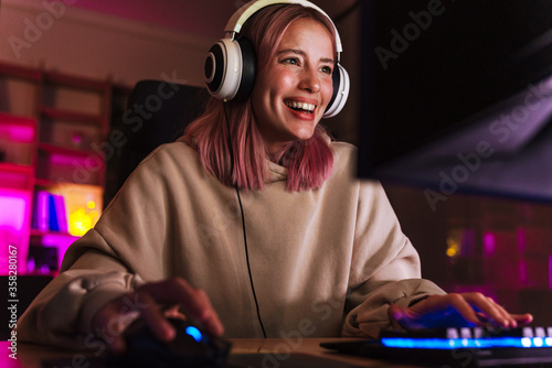 Image of joyful girl smiling and playing video game on computer