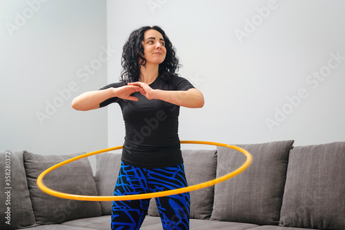 Woman rotating hula hoop. Girl training at home. Healthy sporty lifestyle. photo
