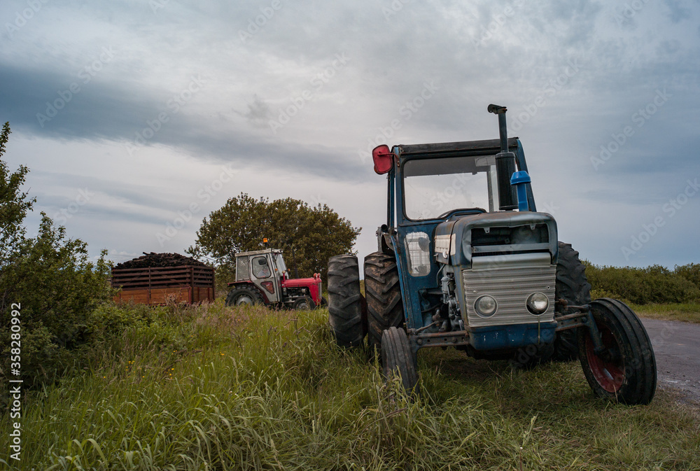 Old tractors and trailers collecting peat bog for fuel in rual Ireland Old tractors and trailers collecting peat bog for fuel in rual Ireland