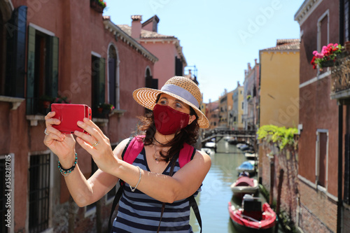 woman with surgical mask and straw hat takes a selfie with smart