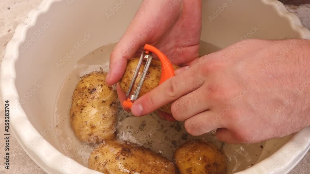 a person peels potatoes with a special tool a person peels potatoes with a special tool