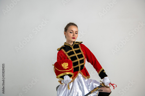 beautiful girl in a red antique hussar costume posing on a white background