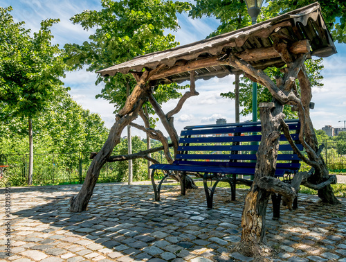 Bench in a public park with a roof made of tree trunks. photo