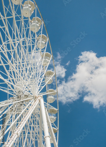 Amusement ride against blue sky. Close up with a white ferrys wheel.