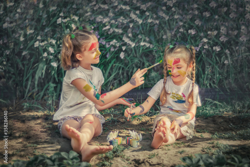 The interaction of children with each other. Girls paint themselves with fun colors