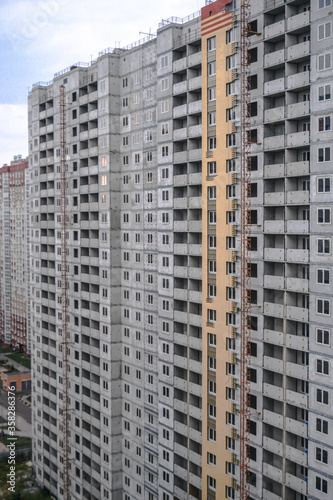 Large construction site on a background of blue sky. Brick, panel apartment building. Industrial theme for design