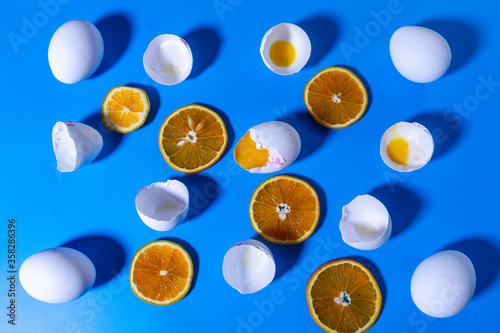 Background. Texture. Chicken eggs, eggshell and chopped oranges on a blue background.