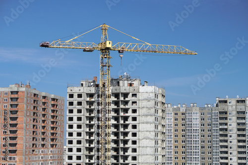 Multi-stage construction during the construction process with a yellow crane. Industrial background for design.