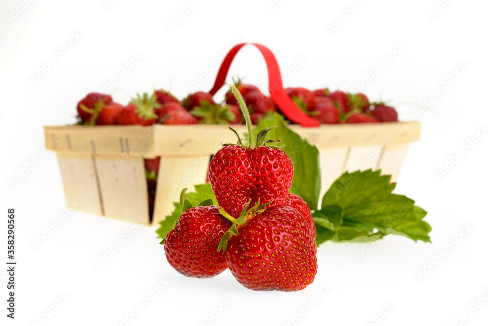 A pile of strawberries with a full basket in the background