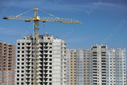 Multi-stage construction during the construction process with a yellow crane. Industrial background for design.