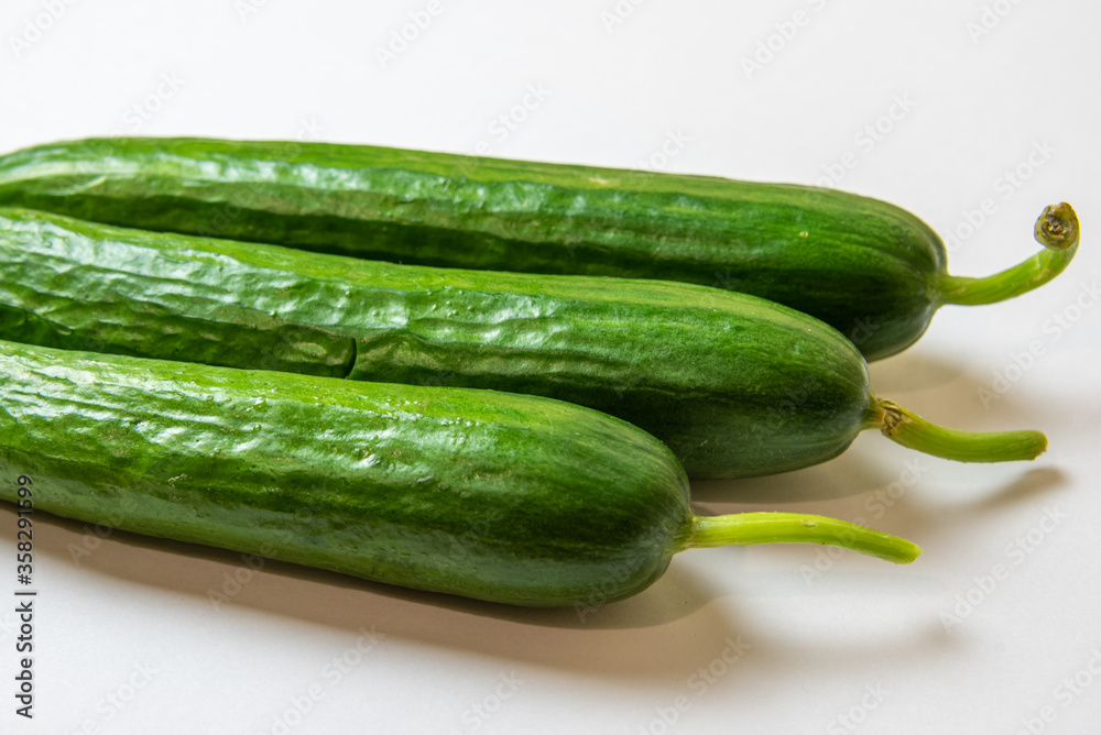 three green fresh cucumbers on a white background