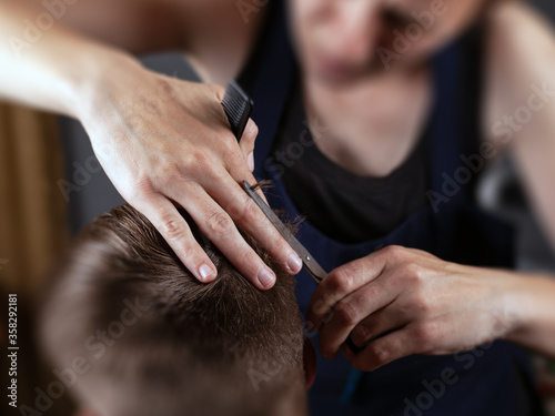 girl cuts guy with scissors and comb, hairdresser concept