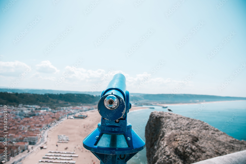large binoculars standing over the ocean shore.