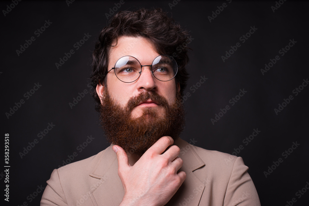 Obraz premium Close up portrait of bearded man wearing eyeglasses and looking away