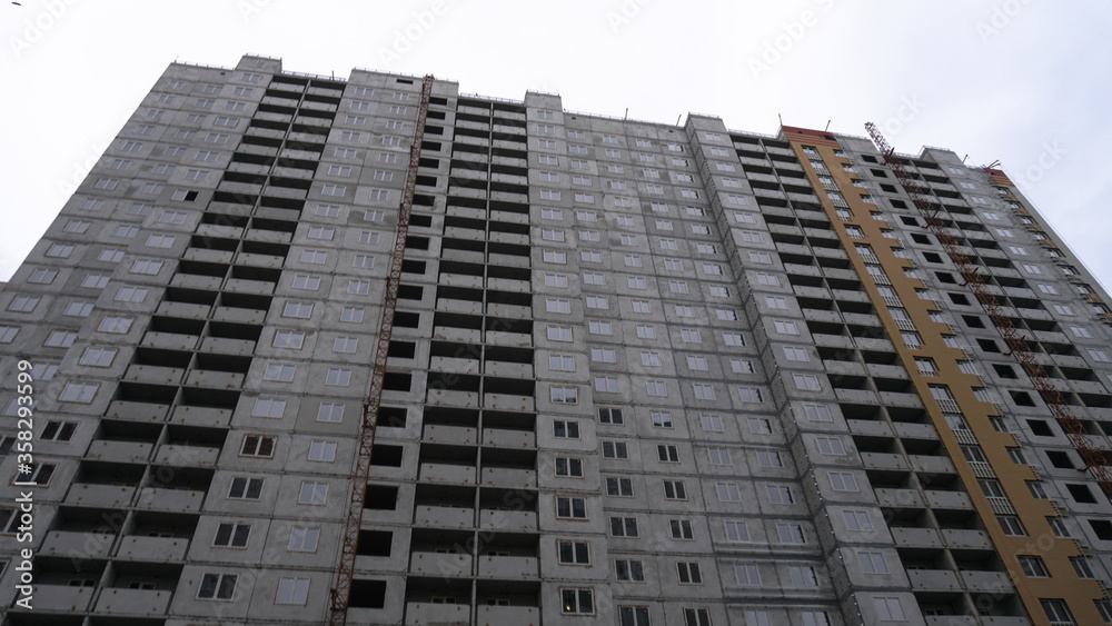 Large construction site on a background of blue sky. Brick, panel apartment building. Industrial theme for design
