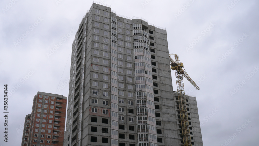 Large construction site on a background of blue sky. Brick, panel apartment building. Industrial theme for design