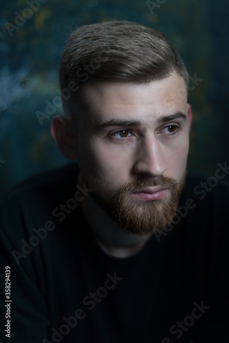 bearded guy portrait of a bearded young guy of twenty-five years old, in black clothes, on a dark background. Studio portrait on black.