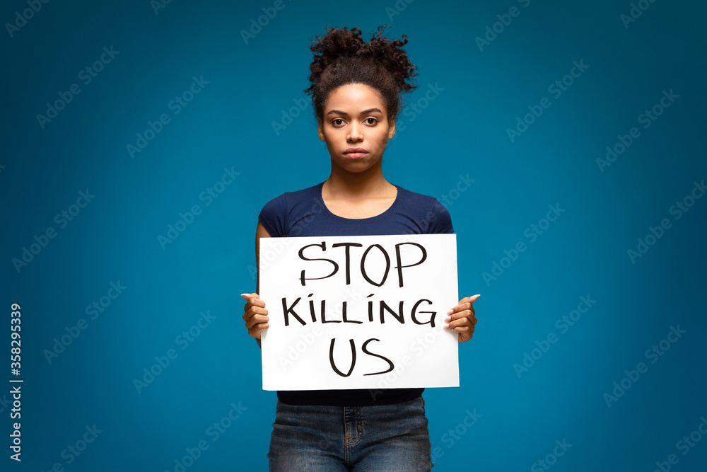 African american woman standing with banner Stop Killing Us African american woman standing with banner Stop Killing Us