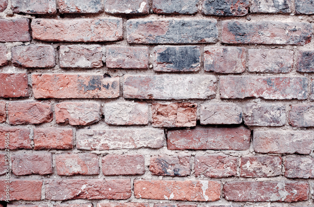 Fragment of an old red brick wall with spots and chips, large brickwork