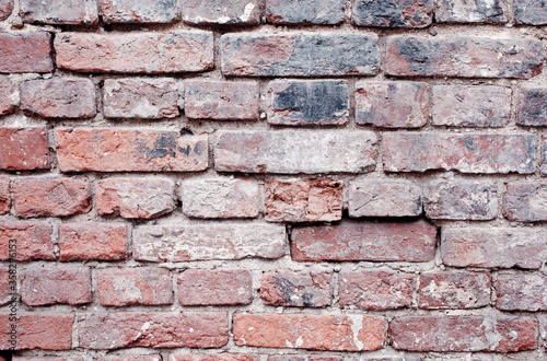 Fragment of an old red brick wall with spots and chips, large brickwork