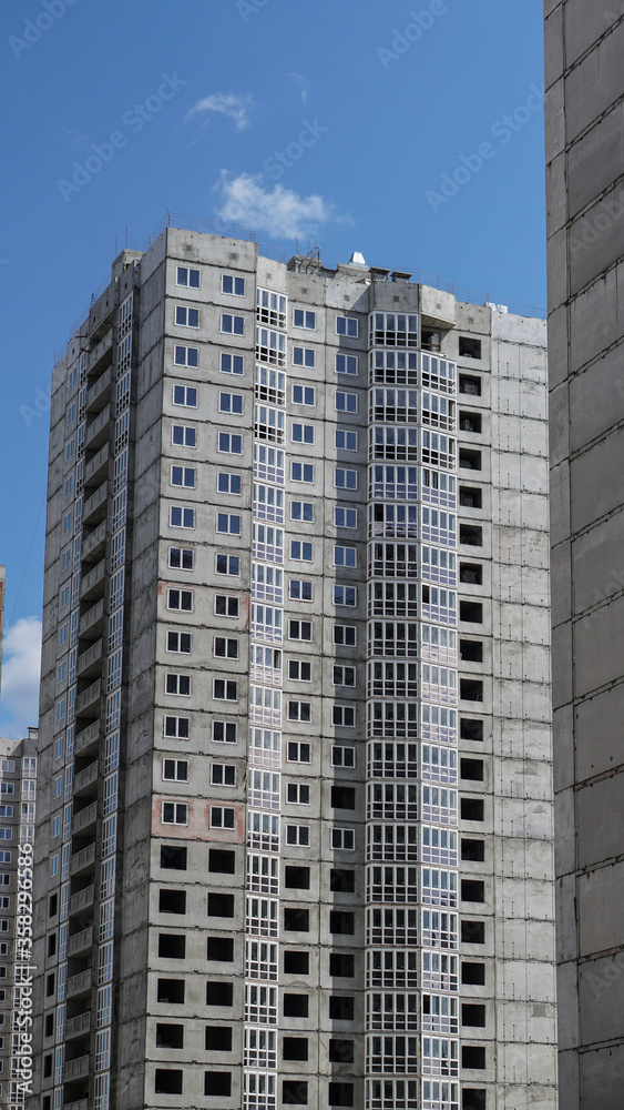 Large construction site on a background of blue sky. Brick, panel apartment building. Industrial theme for design