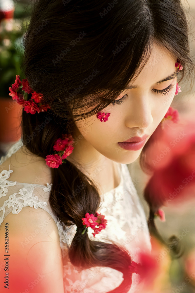 Beautiful Asian fairy in the flowers outdoors, the sun falls on her body