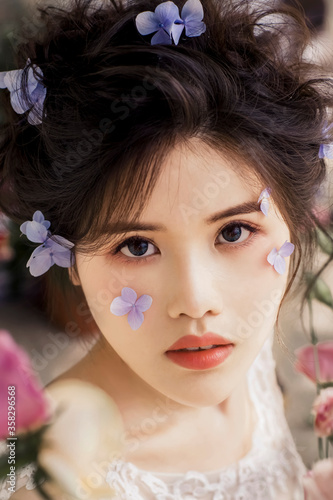 Beautiful Asian fairy in the flowers outdoors  the sun falls on her body