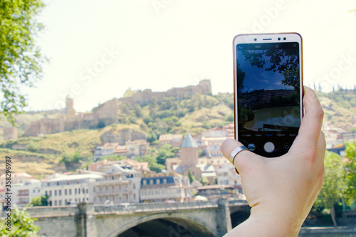 Woman hand and mobile phone, video and photo shooting scene, tourist and traveler take photo and video of old town of Tbilisi