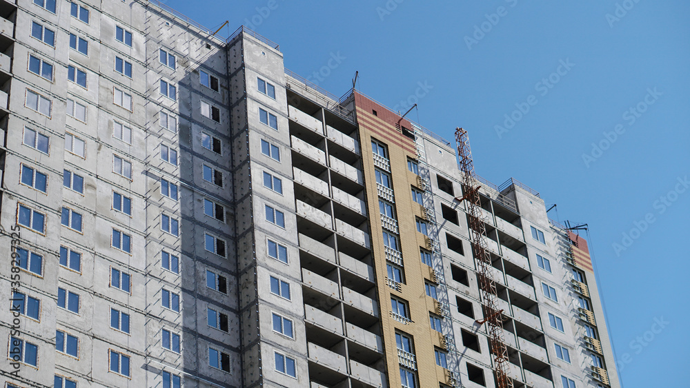 Large construction site on a background of blue sky. Brick, panel apartment building. Industrial theme for design