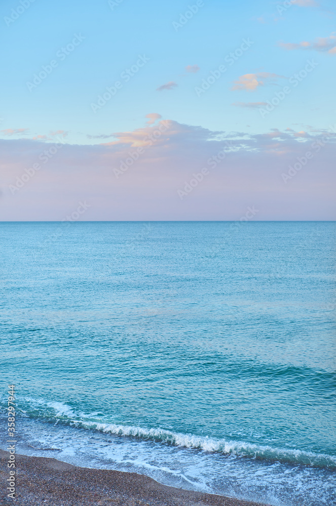 Obraz premium Landscape of the Mediterranean sea without waves at sunset with blue, pink and mauve colors