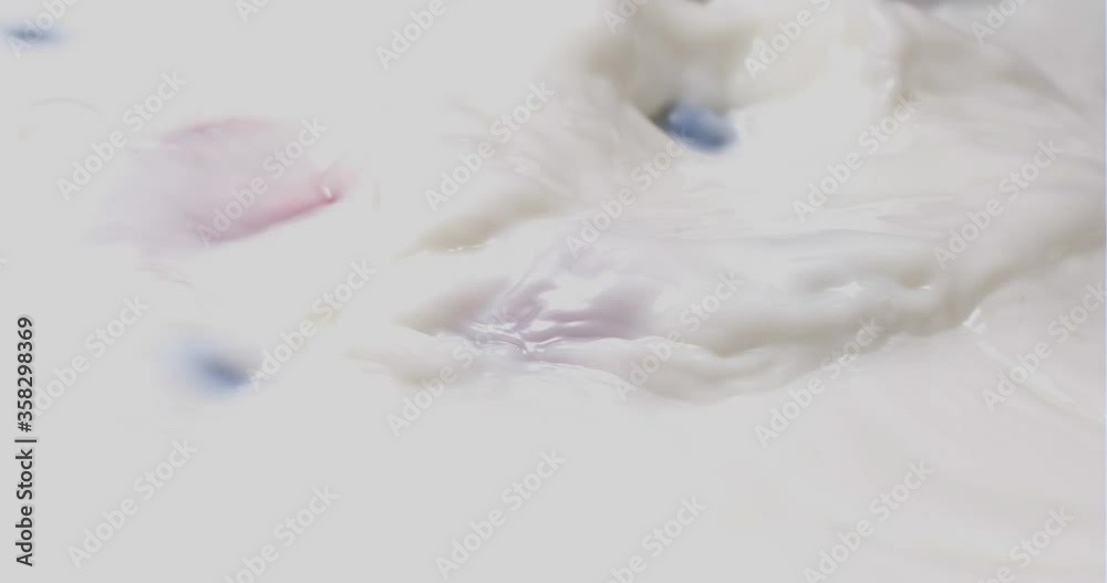 Strawberries and blueberries fall in white milk. Close up, slow motion. Strawberries and blueberries fall in white milk. Close up, slow motion.