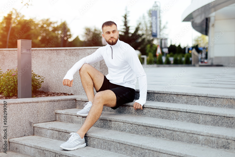 After Training. Cheerful man sitting on steps resting. Fit, fitness, exercise, workout and healthy lifestyle concept. free space for text.
