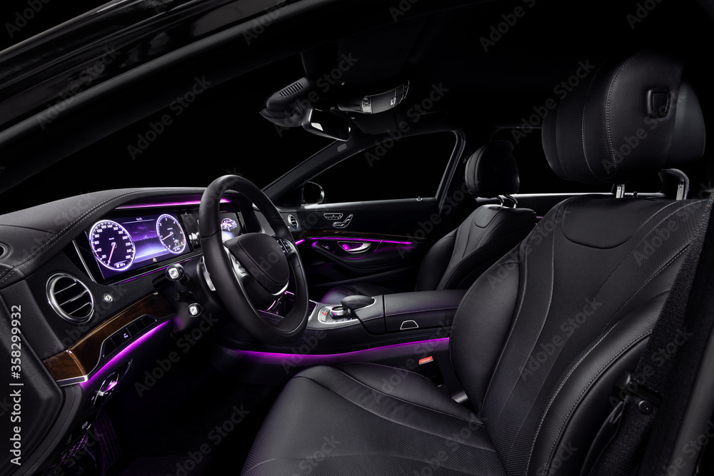 Car interior from driver seat view. Black leather cockpit with violet ambient light.