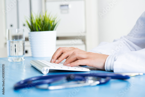 Doctor typing at computer keyboard