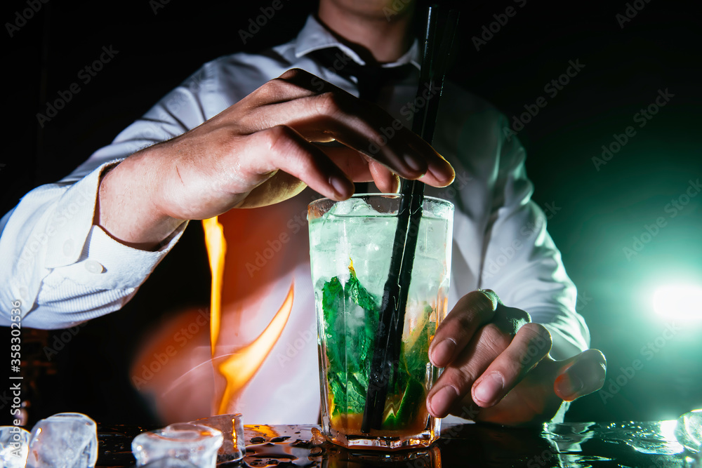 Expert barman making mojito cocktail at the night club. Bartender preparing caipirinha cocktail at the bar counter. 