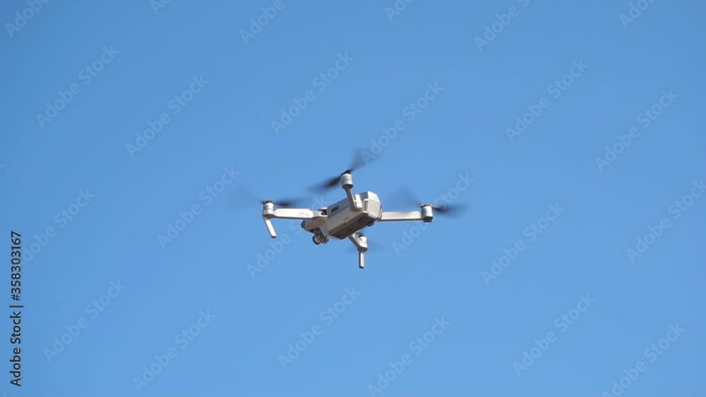 Small quadrocopter flies against a blue cloudless sky, slow motion. Small quadrocopter flies against a blue cloudless sky, slow motion.