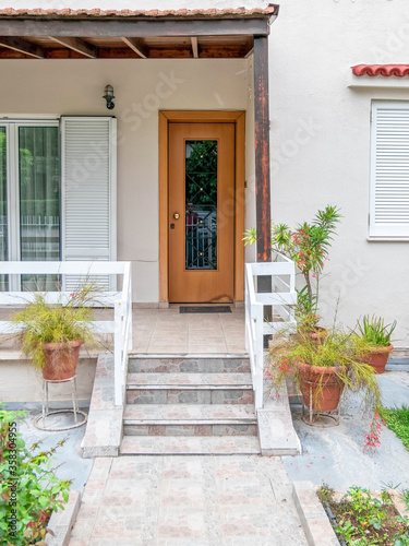 stairs of a family house entrance with natural wood door and flowerpots