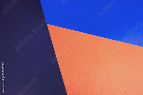 Abstract colored paper backgrounds with copy space. Navy, orange and blue colors. Diagonal geometric composition in dark tones. Top view, flat lay.