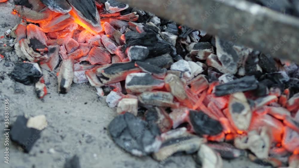 Close-up of glowing and fuming hot coal that is resting on the floor of an outdoor grill. Close-up of glowing and fuming hot coal that is resting on the floor of an outdoor grill.