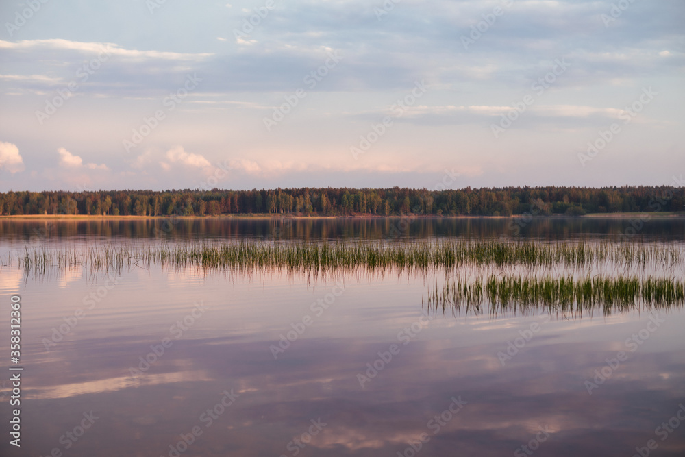 silence in the river, sunset time, background landscape with nice rose clouds. Mirror effect water sky. Summer time vibes