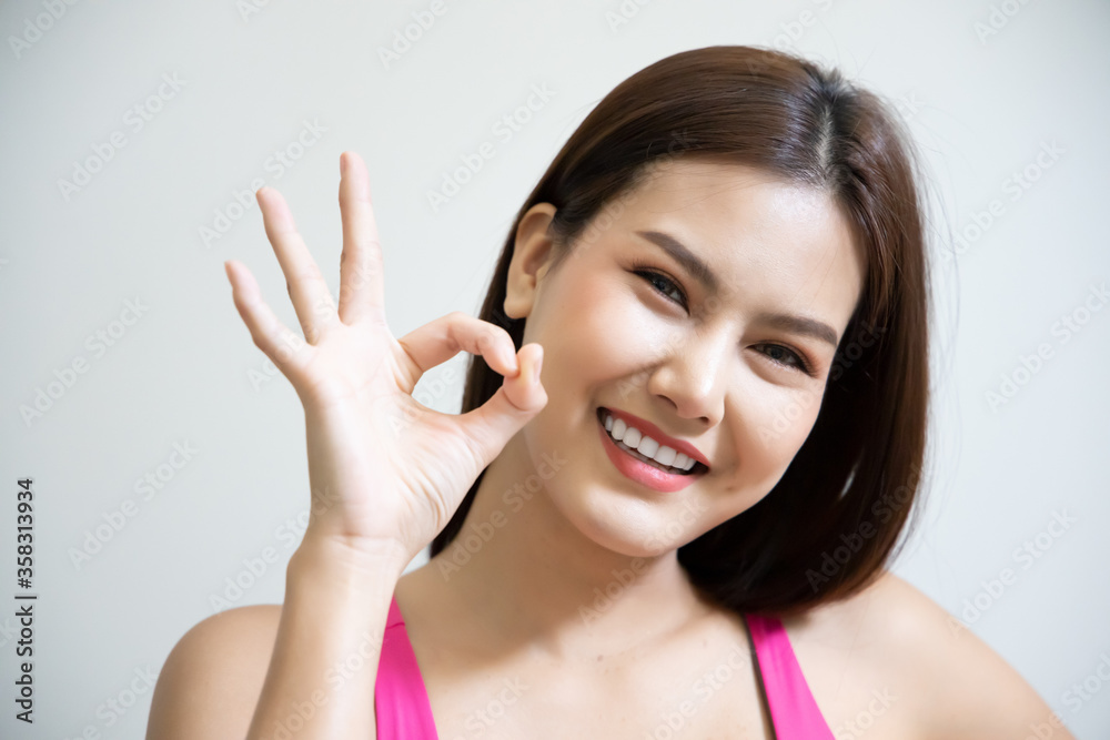 successful girl pointing ok hand sign; portrait of cheerful smiling woman pointing up approving, yes, ok, good, okay gesture; southeast asian woman young adult model successful girl pointing ok hand sign; portrait of cheerful smiling woman pointing up approving, yes, ok, good, okay gesture; southeast asian woman young adult model