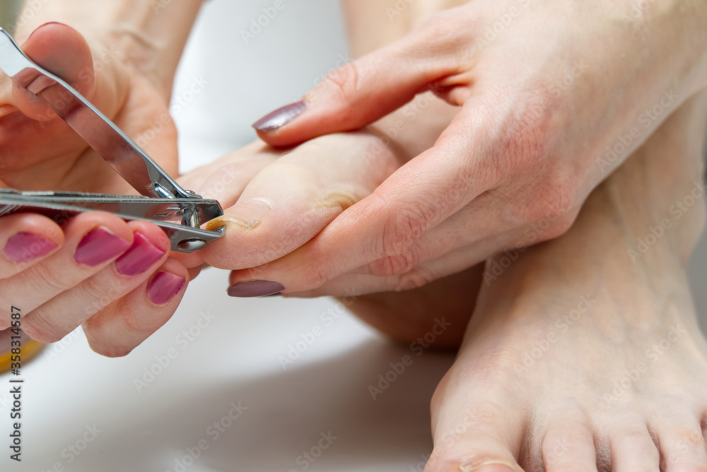 Woman at home spa doing pedicure to herself in white background, close-up. Woman at home spa doing pedicure to herself in white background, close-up.