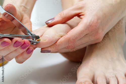 Woman at home spa doing pedicure to herself in white background  close-up.